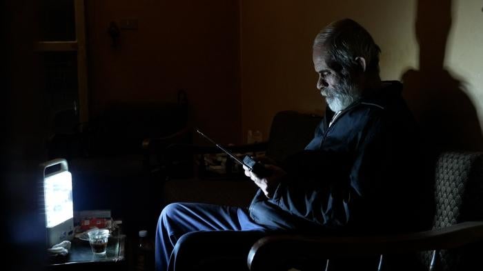 Khodor Al Haushi listens to his battery operated radio in his dark apartment in Beirut, Lebanon.