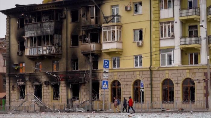 People walk by a burnt out building in Mariupol, Ukraine.