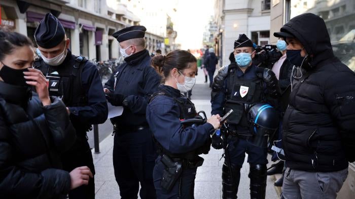 Police officers check IDs of demonstrators near the Palais Vivienne event venue in Paris, France, April 6, 2021.