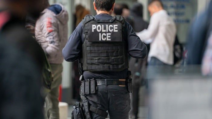 An ICE agent monitors hundreds of asylum seekers being processed upon entering the Jacob K. Javits Federal Building on June 6, 2023 in New York City.